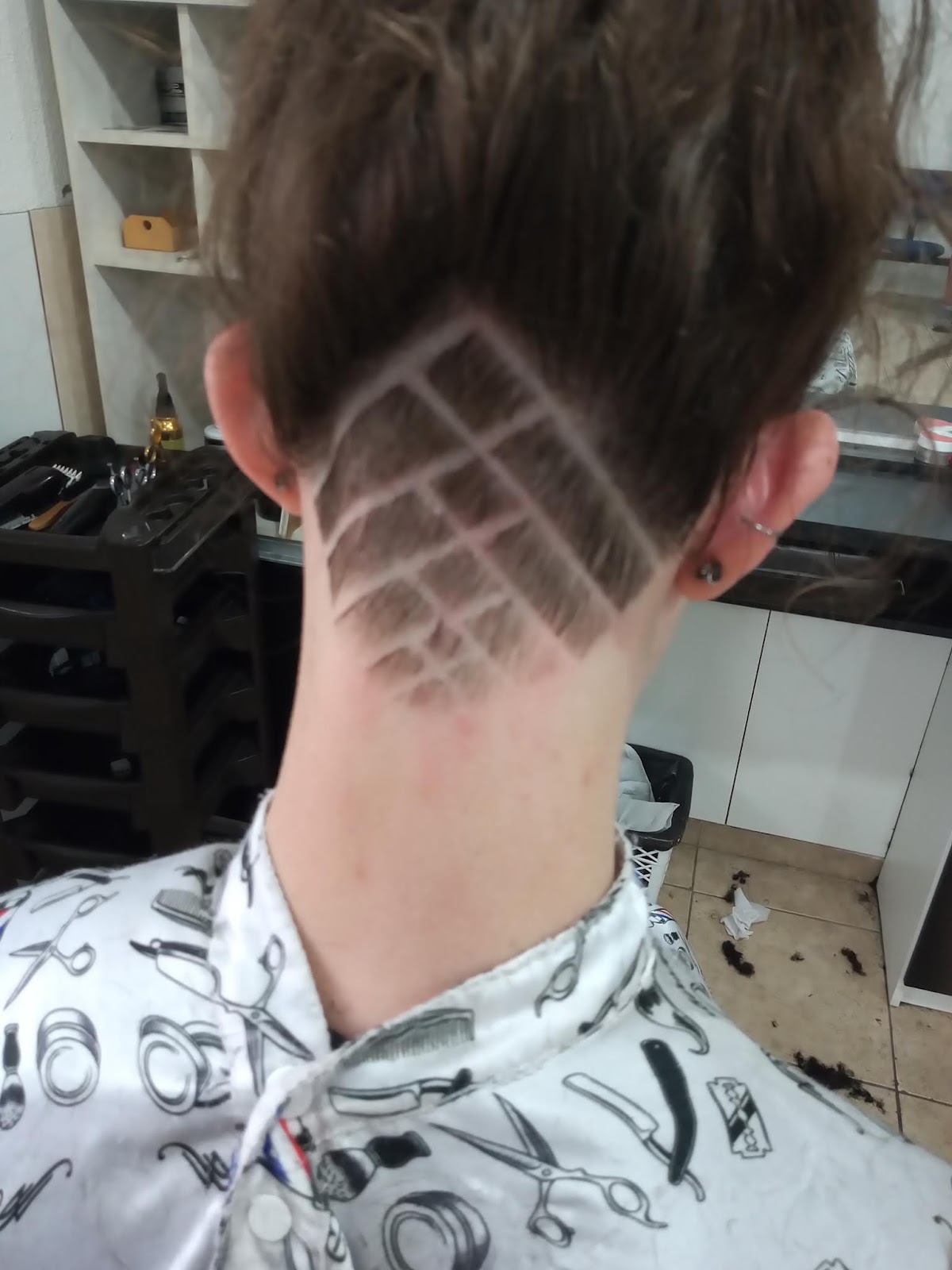 Desenho raspado em grade feito no cabelo de um cliente do Salão Arcelino